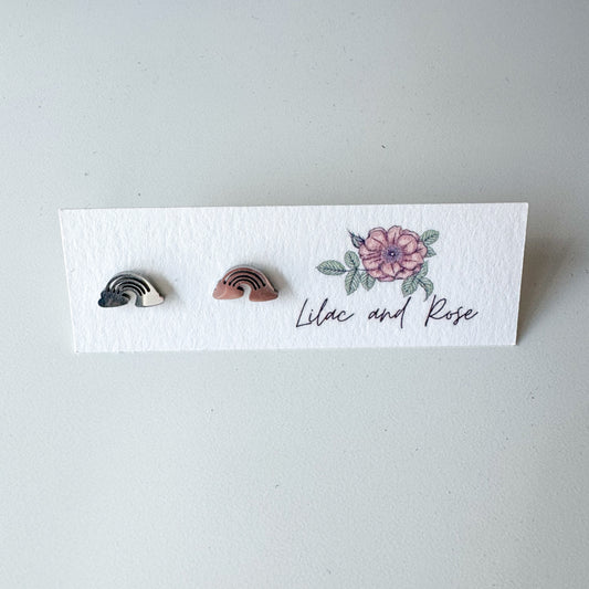 Pair of rainbow-shaped earrings on a 'Lilac and Rose' branded card.