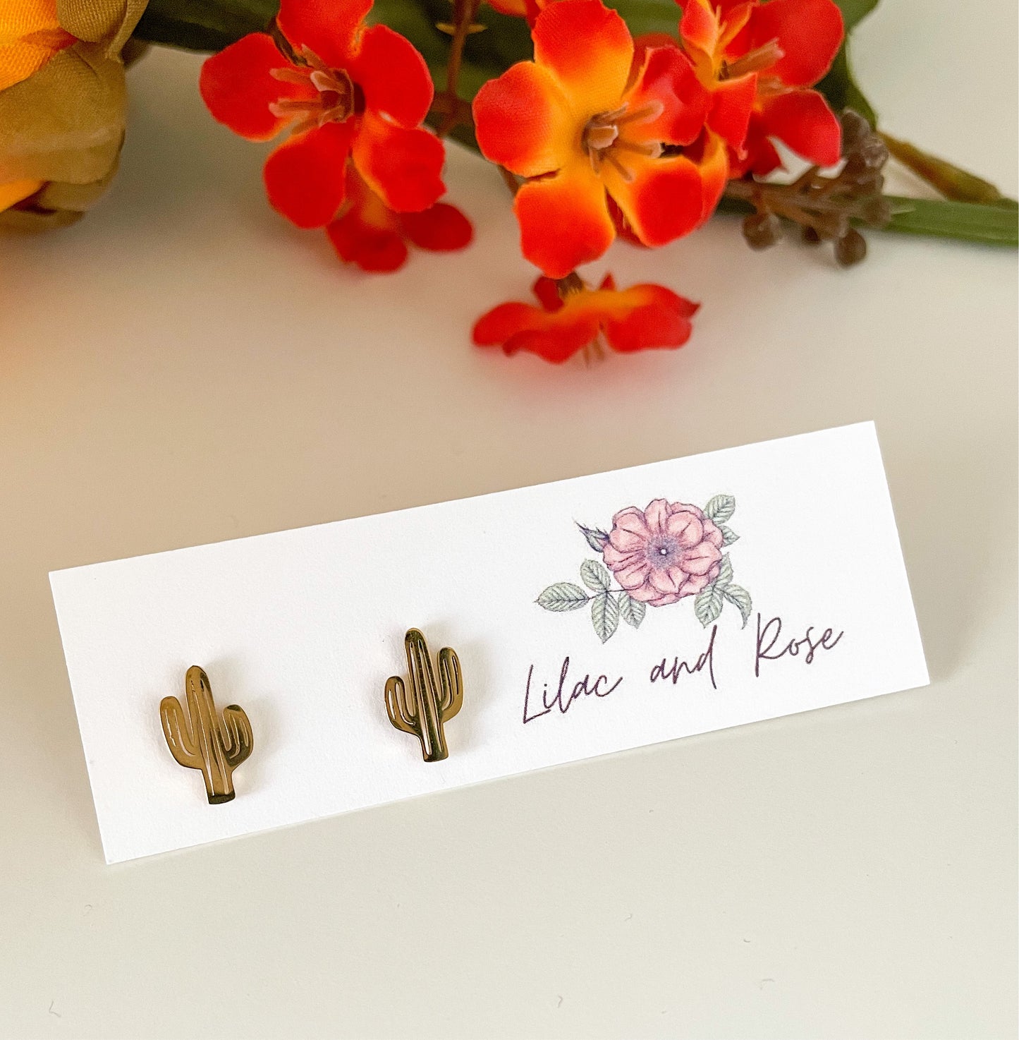 Gold cactus stud earrings on white background