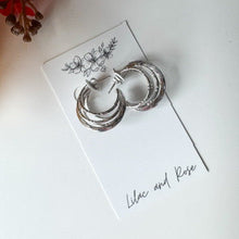 Load image into Gallery viewer, Silver hoop earrings on a white card with floral design, placed on a light surface.
