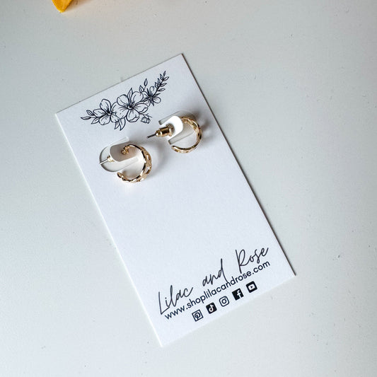A pair of silver mini chain hoop earrings displayed on a white card with floral pattern and the brand name 'Lilac and Rose' written at the bottom.