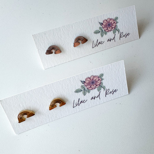 gold and silver rainbow-shaped earrings on white cards with 'Lilac and Rose' branding.