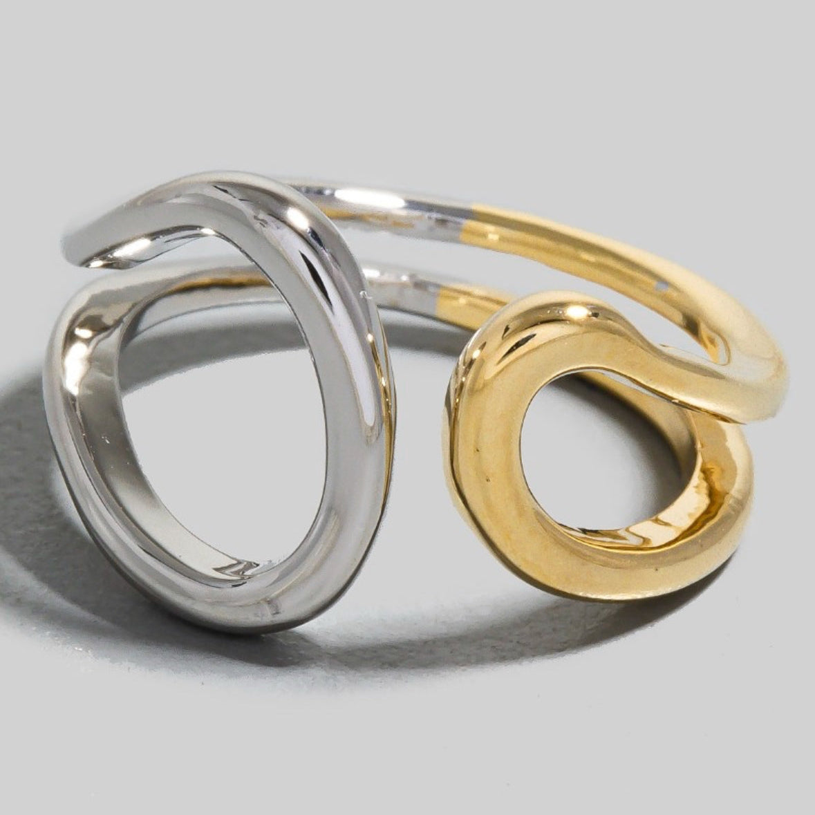 Silver and gold open rings on a light gray background
