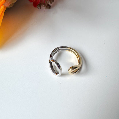 Gold ring on a white surface with flowers in the corner