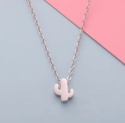 Cactus-shaped pendant necklace on a chain against a pink and blue background