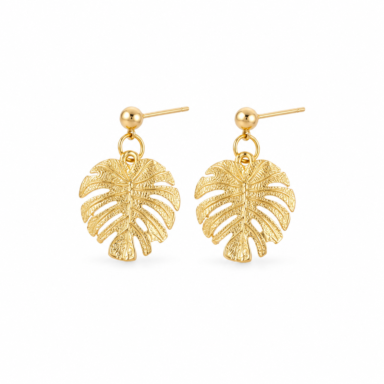 A pair of gold-toned dangle earrings featuring textured monstera leaf charms, shown against a plain white background.