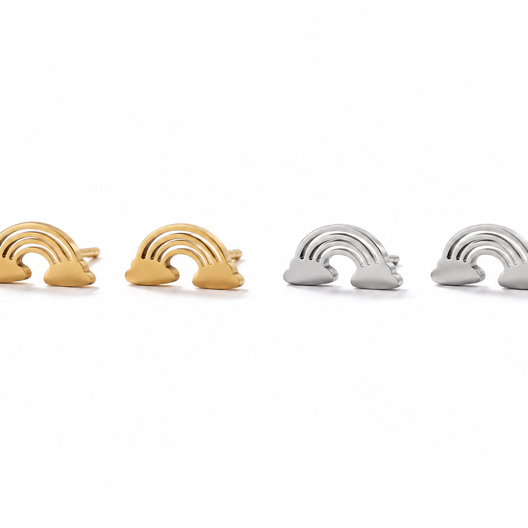Four small rainbow-shaped jewelry pieces arranged in a row on a white background, with two gold-toned pieces on the left and two silver-toned pieces on the right.