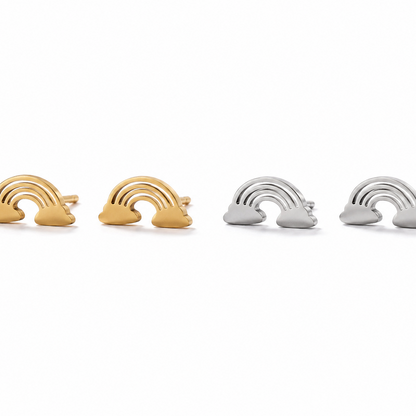 Four small rainbow-shaped jewelry pieces arranged in a row on a white background, with two gold-toned pieces on the left and two silver-toned pieces on the right.